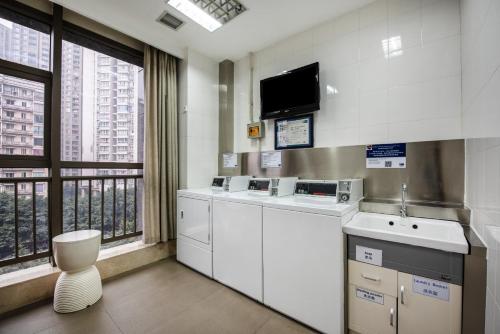 重庆重庆观音桥智选假日酒店的厨房配有白色橱柜和平面电视。