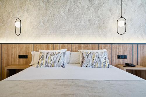英格兰海滩Bull Vital Suites & Spa Boutique Hotel - Only Adults的一间卧室,床上方有两盏灯