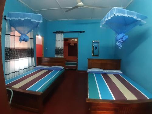 亭可马里阿米拉旅馆的蓝色墙壁客房的两张床
