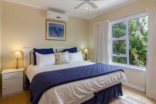 滨海肯顿Dunwerkin Self Catering的一间卧室配有一张带蓝色棉被的床和窗户。