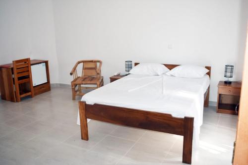 圣多美Residencial Aeroporto的卧室配有1张床、1张桌子和1把椅子