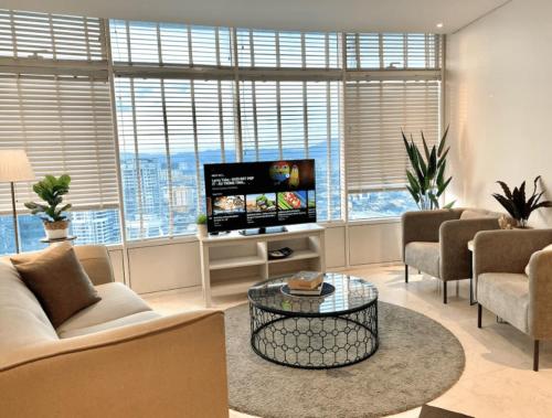 吉隆坡Vortex KLCC Apartment Kuala Lumpur的客厅配有电视、一些椅子和一张桌子