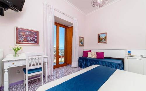 阿马尔菲拉布索拉酒店的一间卧室配有一张床、一张书桌和一个窗户。