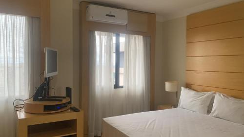 圣保罗Quarto em hotel pertinho do aeroporto/ Congonhas的一间卧室设有一张床、一台电视和一个窗口。