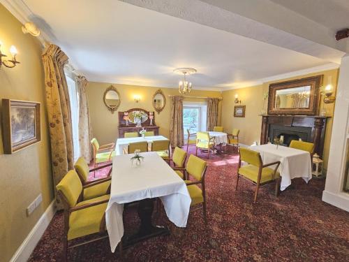 格伦贝赫The Glenbeigh Hotel的用餐室配有2张桌子和黄色椅子