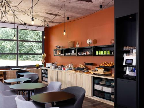 莱斯坎四季里尔机场酒店的餐厅拥有橙色的墙壁和桌椅