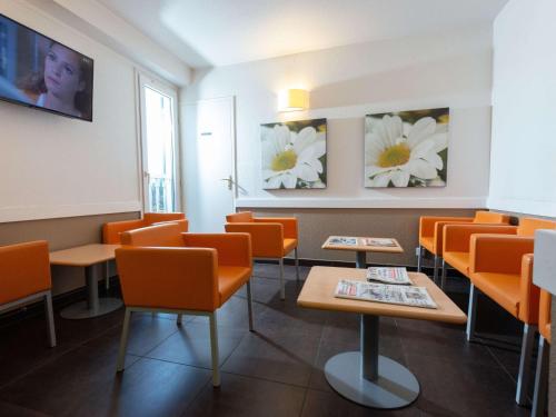 马孔宜必思梅肯苏德经济酒店的一间设有橙色椅子和鲜花的等候室