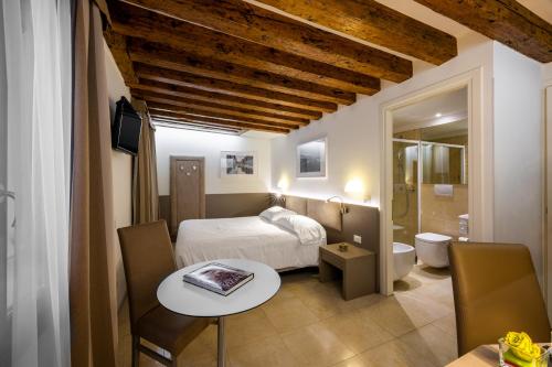 威尼斯Leone Hotel的一间卧室配有一张床铺和一张桌子,还有一间浴室