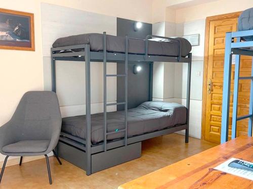 福米加尔Apartamentos Midi 3000的带两张双层床和椅子的房间