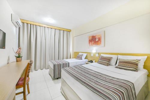 皮拉西卡巴Hotel Nacional Inn Piracicaba的酒店客房配有两张床和一张书桌
