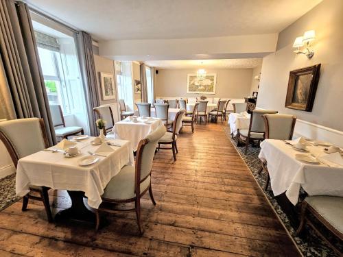 格伦贝赫The Glenbeigh Hotel的用餐室配有桌椅和白色的桌布