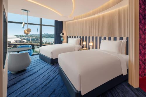 悉尼W Sydney的酒店客房设有两张床和一张桌子。