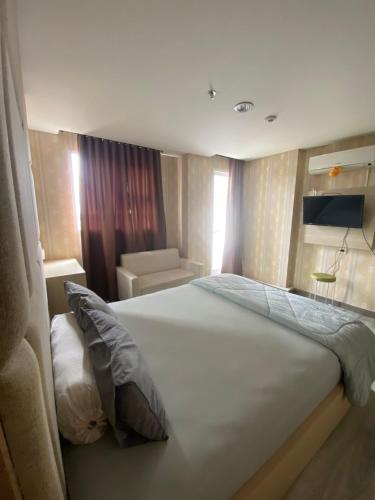Pondokarenapartemen bintaro icon的卧室配有一张白色的大床和一张沙发。