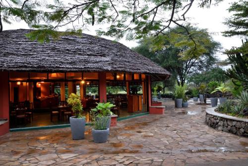 阿鲁沙Kia Lodge的一间拥有茅草屋顶和庭院的餐厅