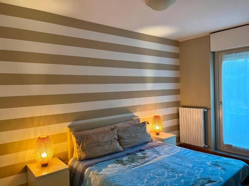贝加莫Bergamo Bilocale Nuovo in centro 4 posti Letto的一间卧室设有条纹墙、一张床和两盏灯