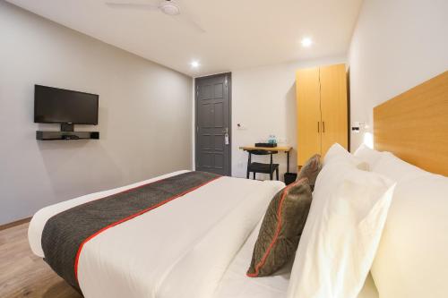 古尔冈Townhouse Near Appu Ghar的卧室配有一张床,墙上配有电视。