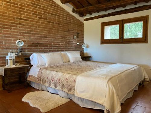 Els HostaletsHabitación suite en Masía Can Robira的一间卧室设有一张床和砖墙
