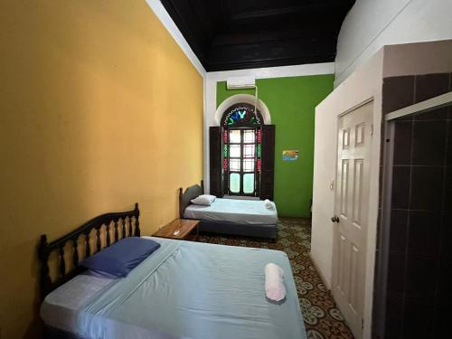 圣安娜Hostal Plaza Antigua的配有两张床的客房,设有绿色的墙壁和窗户