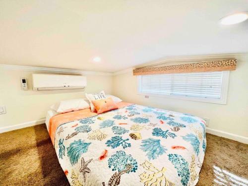 默特尔比奇Vacation Cottage North Myrtle Beach 67的一间卧室配有一张带五颜六色的被子的床和窗户
