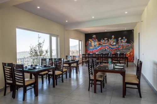 穆克缇斯瓦Shree Parijat Resort At Mukteshwar Hill Station with Himalayan View的餐厅设有桌椅,墙上挂有绘画作品