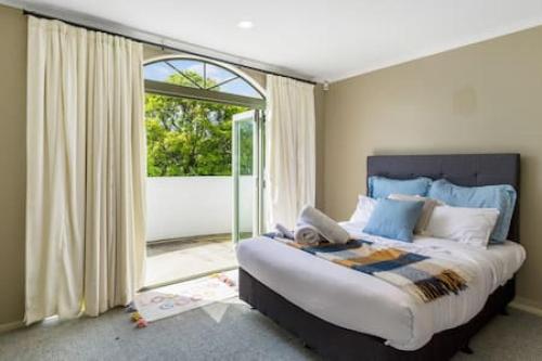 奥克兰Nature Serenity Getaway with pool - deck - gardens的一间卧室设有一张大床和一个大窗户