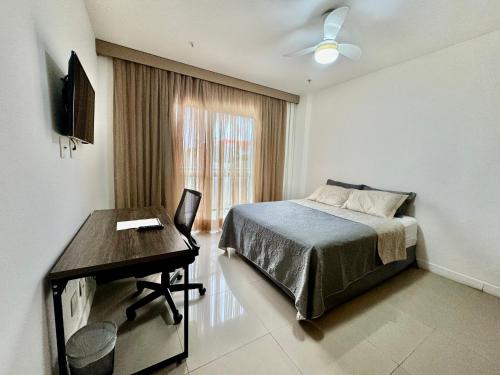 里约热内卢Suite privativa na Barra da Tijuca, RJ - Neolink Stay的一间卧室配有一张床、一张书桌和一个窗户。