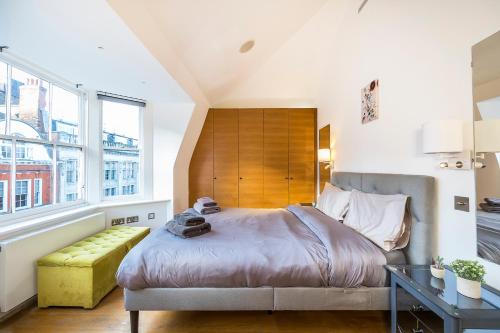 伦敦Lux Duplex near Oxford St的一间卧室设有一张大床和一张黄色长凳