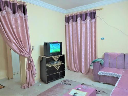 明亚Furnished Apartment的客厅配有电视和粉红色窗帘