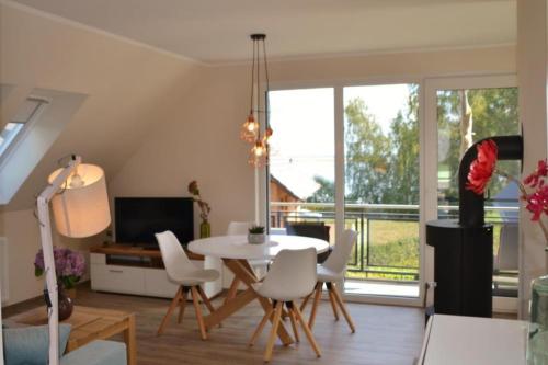 勒伯尔U15 OG - Komfortable Ferienwohnung mit Balkon & Kamin in Röbel an der Müritz的客厅配有白色的桌子和椅子
