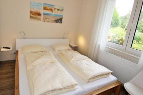 马林费尔德U17 EG - komfortable Ferienwohnung mit Terrasse, Wlan und Kamin的带窗户的客房内的两张床
