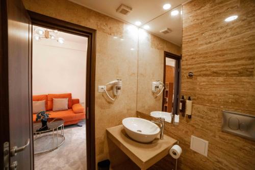 奥托佩尼Bucharest Airport Accomodation的一间带水槽和橙色沙发的浴室
