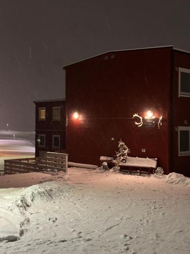朗伊尔城豪根斯瓦尔巴旅馆的雪中带灯的建筑物