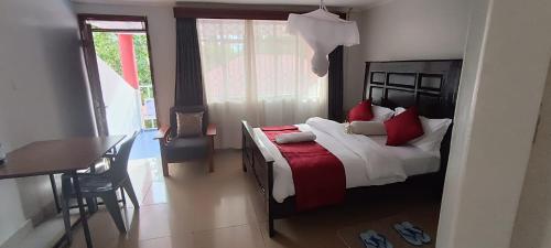 基苏木Milimani Comfort的一间卧室配有一张带红色枕头的床和一张桌子