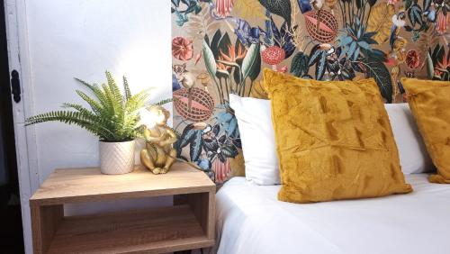 伦敦3 bed flat O2 arena Dyson house的一张带黄色枕头的床和一张带植物的桌子