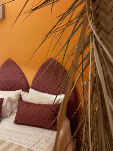 马拉喀什RIAD DAR NAOMI的一张带红白枕头和植物的床
