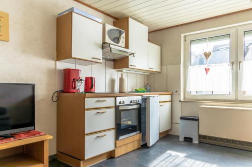 恩基尔希Moselträubchen的一间小厨房,配有白色的橱柜和一台电视