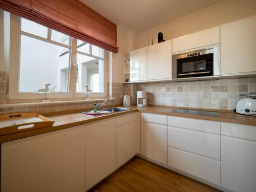宾茨Ferienwohnung 560 in der Villa Gudrun的厨房配有白色橱柜、水槽和窗户。
