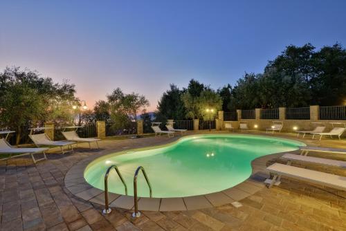 圣塔马里亚迪卡斯特艾拉雅别墅酒店的夜间游泳池,配有椅子和桌子