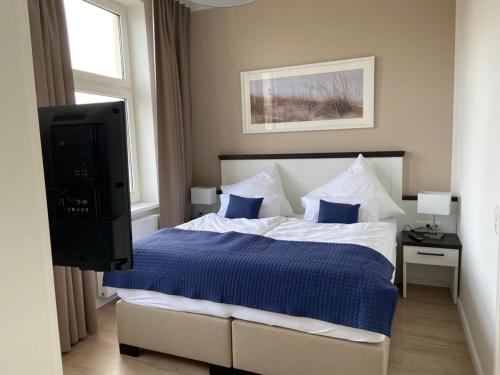 诺德奈Inselhuus Felimar的一间卧室配有一张带蓝色床单的床和电视。
