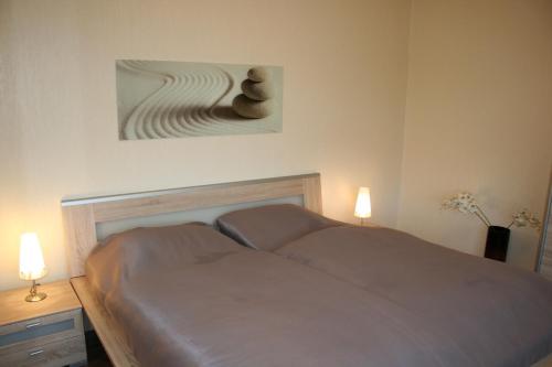 库克斯港Watten-Blick 1的一间卧室配有一张带两盏灯和一幅画的床铺