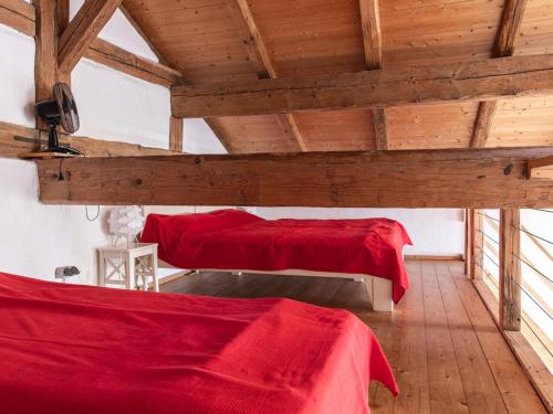 SchernfeldNEU! Studio Beim Kirchschuster的木天花板客房中的两张床,配有红色床单