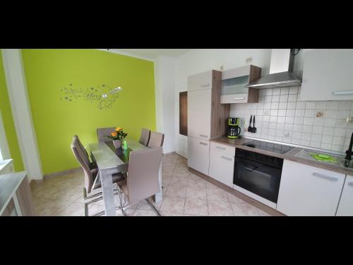 施瓦岑贝格NEU! Ferienwohnung Unger的厨房配有桌椅和绿色的墙壁