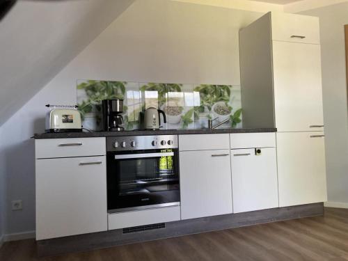 胡苏姆NEU Ferienwohnung Hofmann的厨房配有白色橱柜和烤箱。