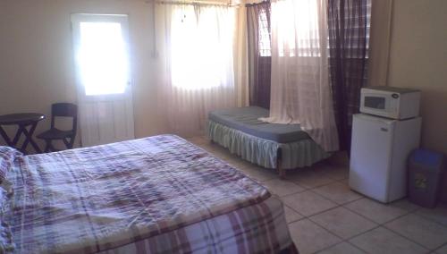 Maracas Bay VillageMaracas Bay View的一间卧室配有一张床和一把椅子,还有两个窗户