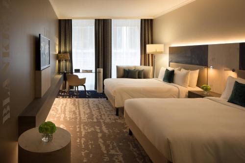 汉堡汉堡万丽酒店的酒店客房设有两张床和一张桌子。