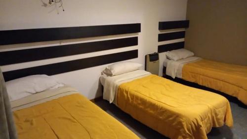 瓜伊马延Hostel Los Andes的一间设有三张黄色床单的房间