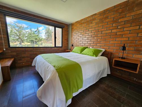 ChasquiEl Chasqui Guest House的一间卧室设有一张大床和砖墙