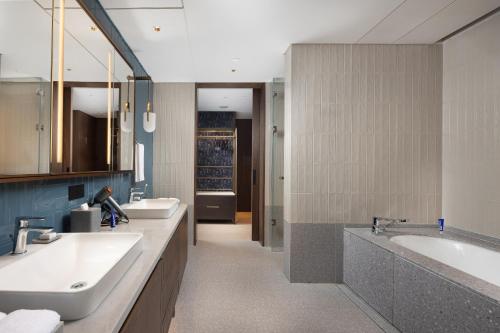 广州广州新世界酒店的浴室配有2个盥洗盆、浴缸和2个盥洗盆。
