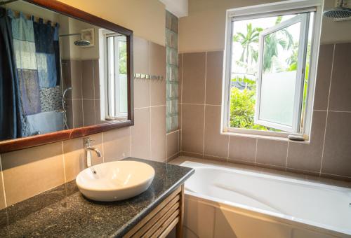 顺化Lagom Home的一间带水槽和浴缸的浴室以及窗户。