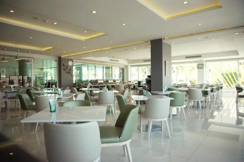 罗勇Tamarind Garden Hotel - SHA Plus Certified的餐厅设有白色的桌子和绿色的椅子